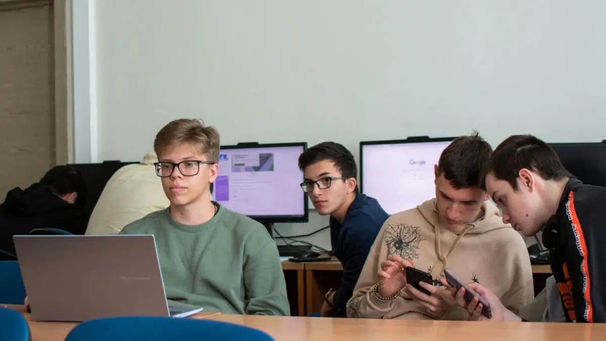 Four male students in a computer room working together on a project.