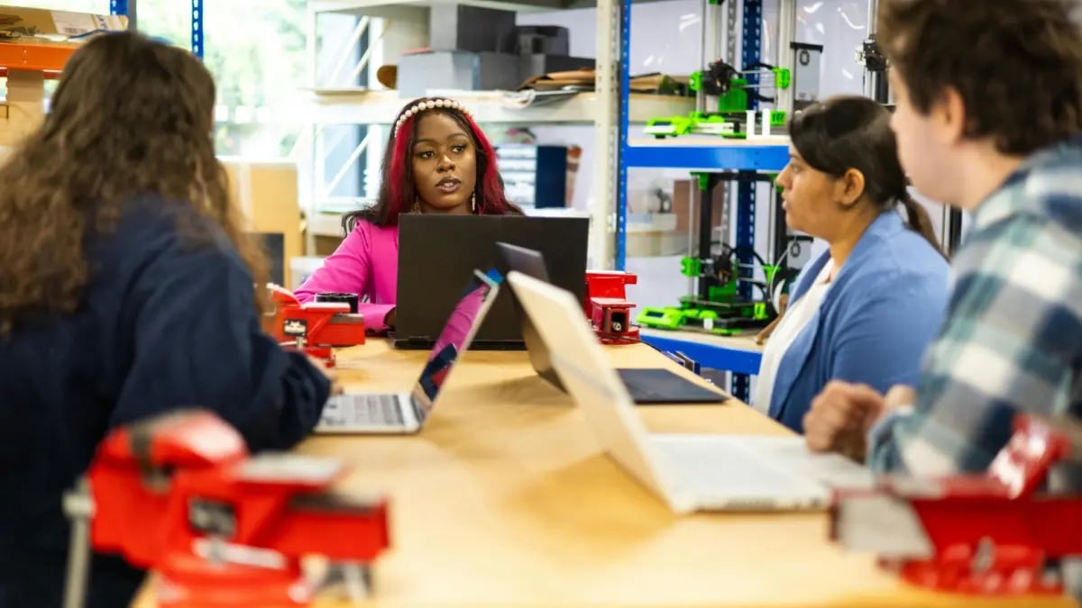 Students on laptops in engineering class looking at teacher.
